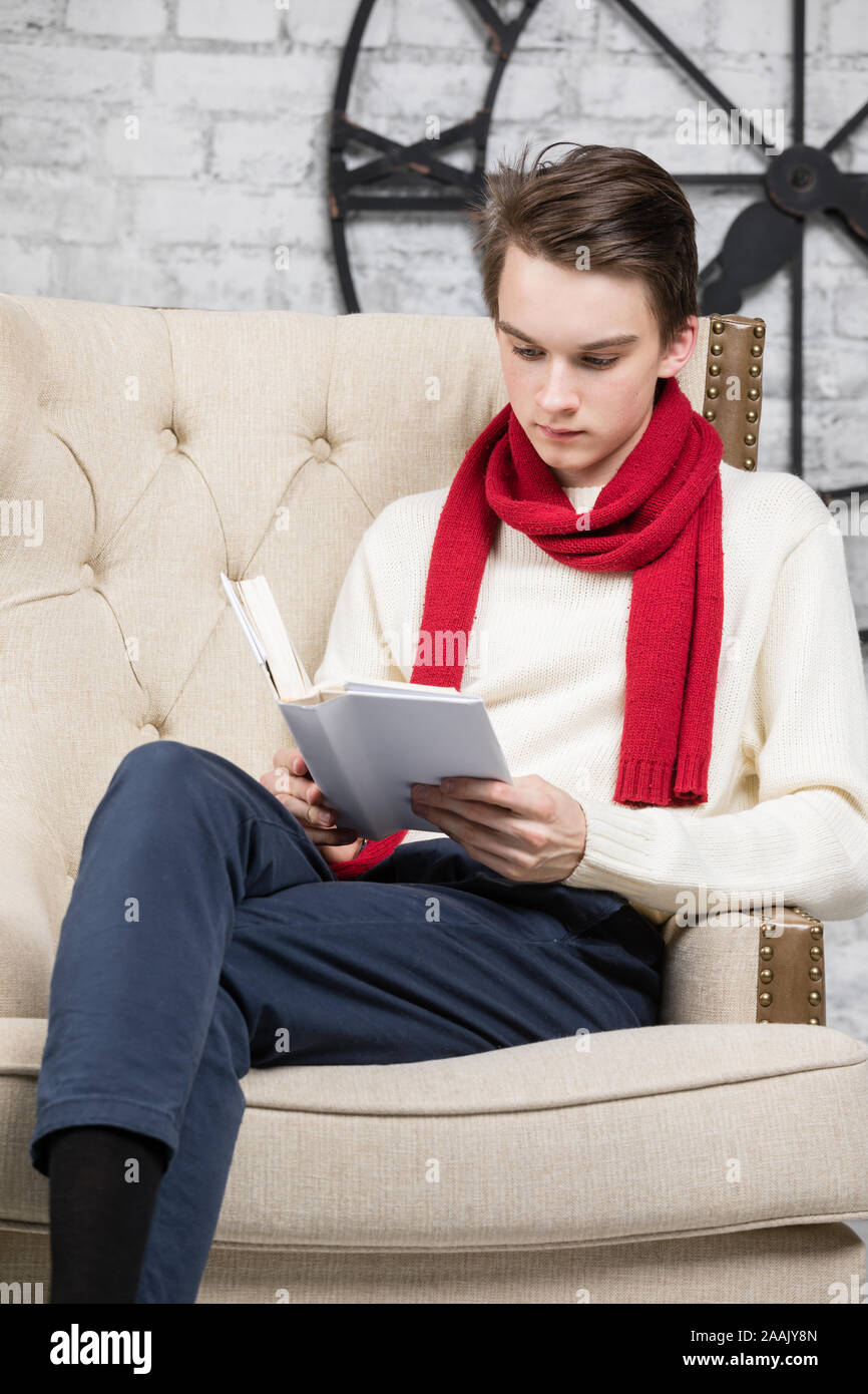 Adolescents portant foulard rouge et blanc pour homme assis dans un  fauteuil à la maison Lire un livre Photo Stock - Alamy