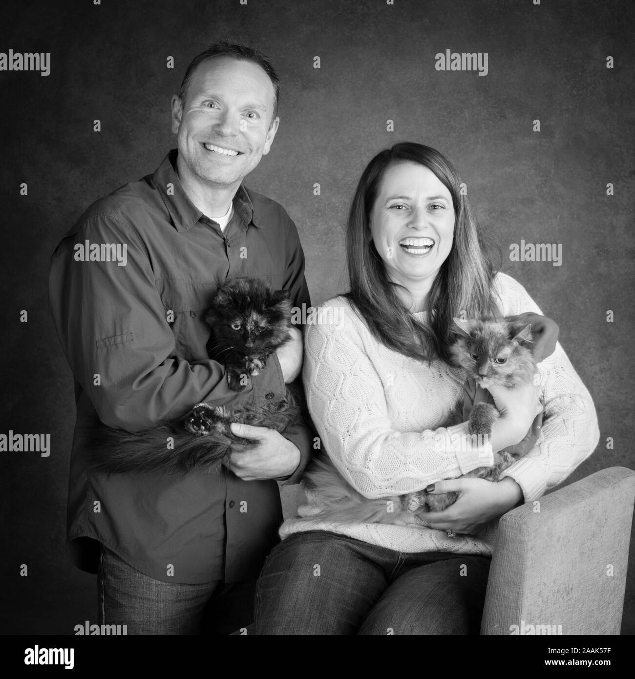 Studio portrait of smiling woman and man avec deux chats à poils longs Banque D'Images