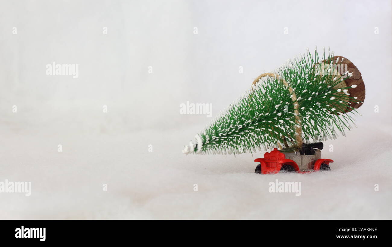 Toy voiture transportant un arbre de Noël dans un paysage enneigé. L'espace pour le texte. Banque D'Images