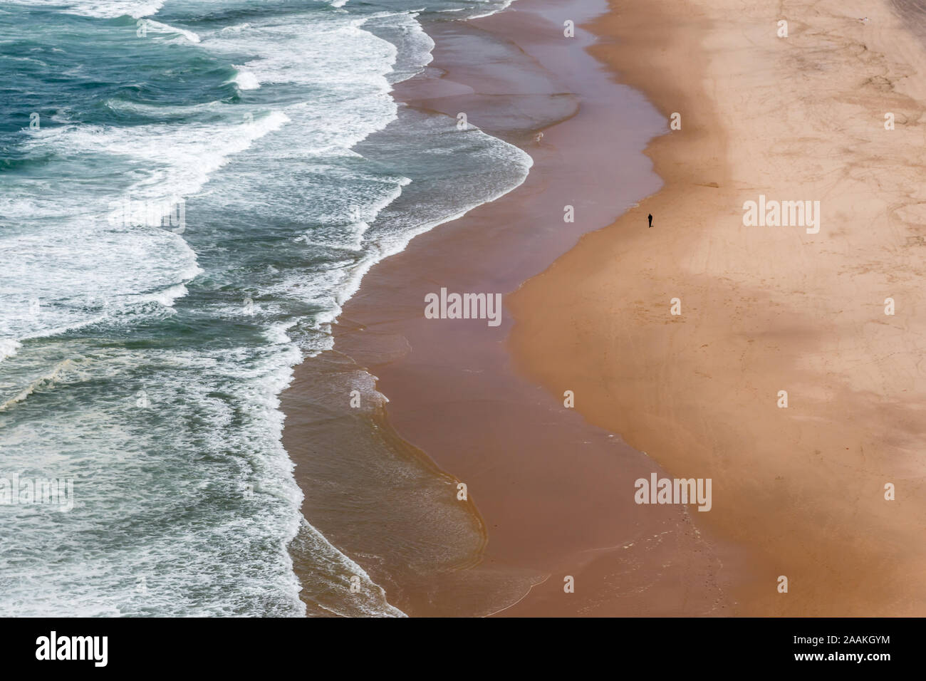 Les seule personne à marcher le long du bord de l'eau vide Praia Grande plage de sable près de Sintra Portugal en été Banque D'Images