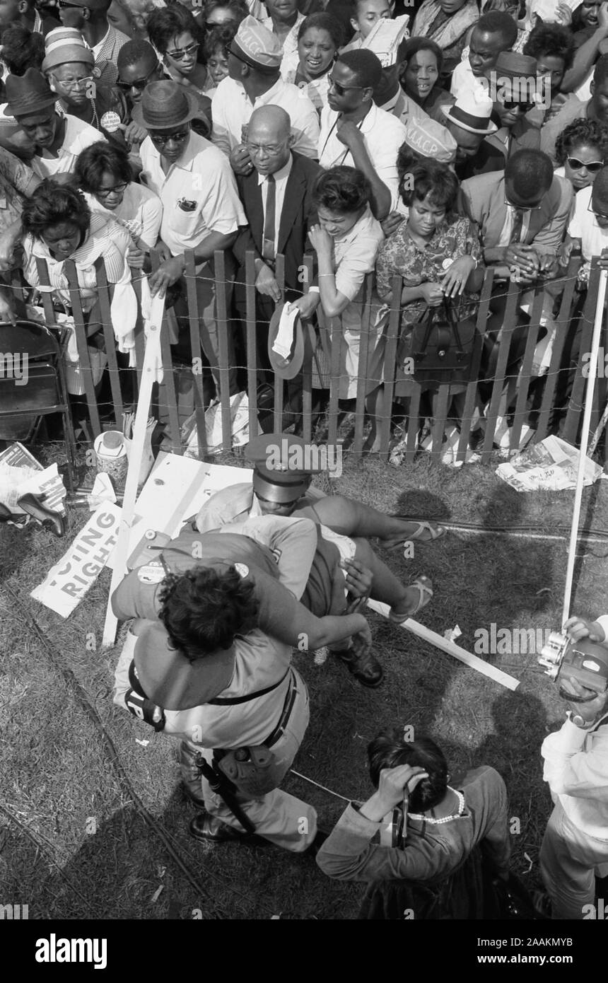 Foule des Américains africains derrière une clôture de tempête avec la police transportant une femme de l'autre côté en Mars sur Washington pour l'Emploi et de la liberté, Washington, D.C. USA, Photo de Marion S. Trikosko, 28 août, 1963 Banque D'Images Foule des Américains africains derrière une clôture de tempête avec la police transportant une femme de l'autre côté en Mars sur Washington pour l'Emploi et de la liberté, Washington, D.C. USA, Photo de Marion S. Trikosko, 28 août, 1963 Banque D'Images