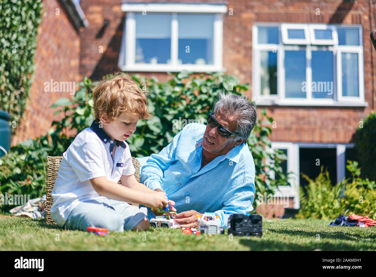 Grand-père petit-fils regarder jouer sur l'herbe Banque D'Images