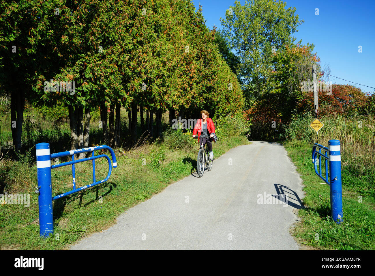 Femme d'âge moyen de la bicyclette sur la piste cyclable près de Terrebonne, province de Québec, Canada. Banque D'Images