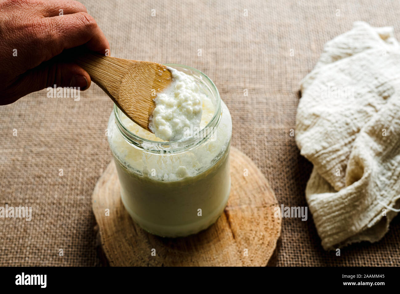 La main de l'homme verse le kéfir de lait dans un pichet de préparer un petit-déjeuner sain pour le microbiote intestinal. Banque D'Images