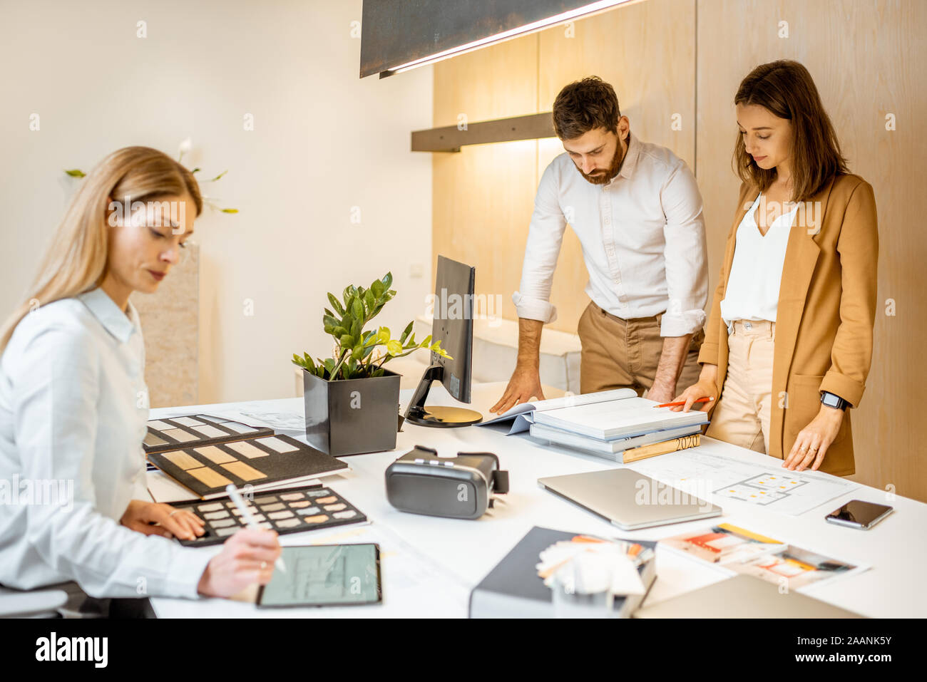Les jeunes employés habillés à la légère de faire certains travaux de création à la grande table avec les ordinateurs dans le bureau. Concept d'une entreprise d'architecture et de création Banque D'Images