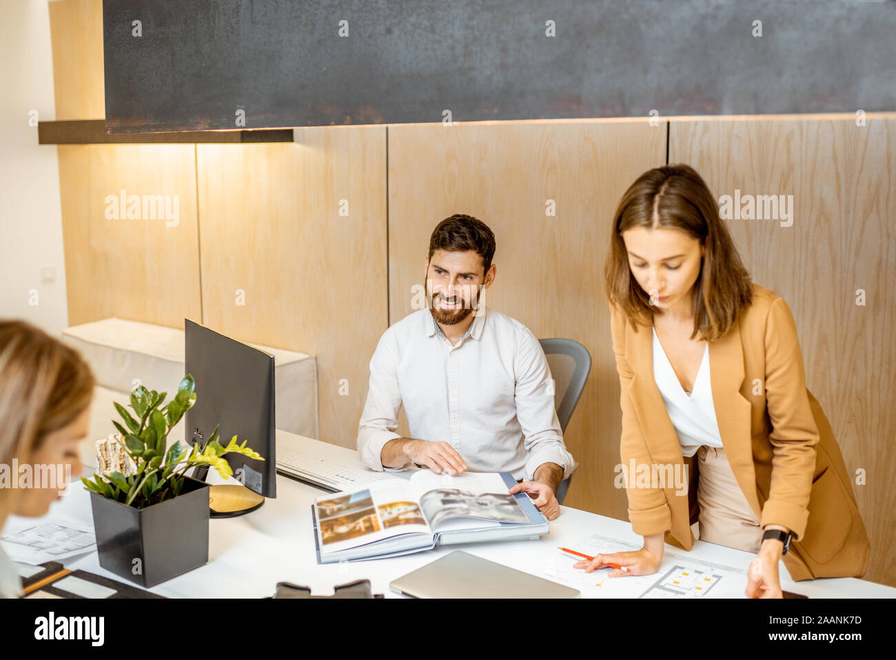 Les jeunes employés habillés à la légère de faire certains travaux de création à la grande table avec les ordinateurs dans le bureau. Concept d'une entreprise d'architecture et de création Banque D'Images