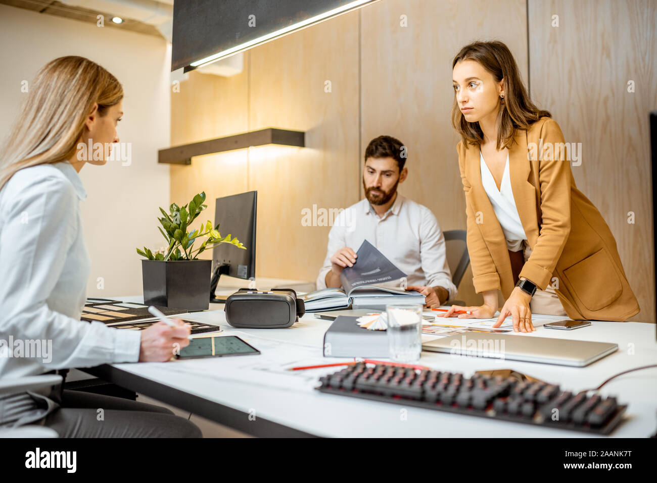 Les jeunes employés habillés à la légère de faire certains travaux de création à la grande table avec les ordinateurs dans le bureau. Concept d'une entreprise d'architecture et de création Banque D'Images