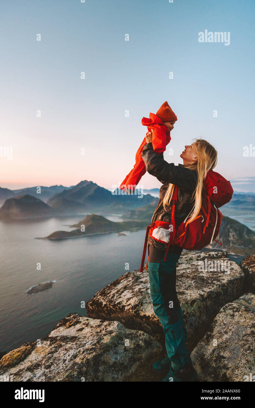 Mother holding up baby voyages randonnées en montagne de vie sain de la famille maman avec sac à dos et de l'enfant de plein air vacances actives en Norvège Lofo Banque D'Images
