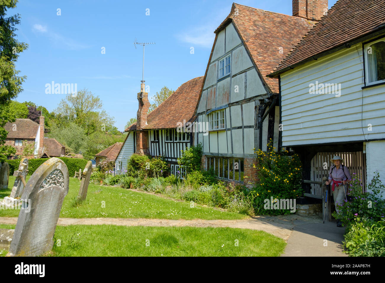 Un marcheur par la cité médiévale cottages bordant le cimetière, Smarden, Kent, UK Banque D'Images