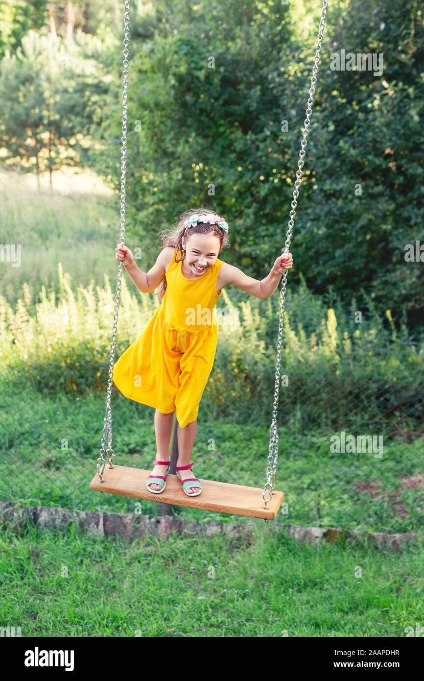 Belle teen girl standing on swing au jour d'été, enfance heureuse concept Banque D'Images