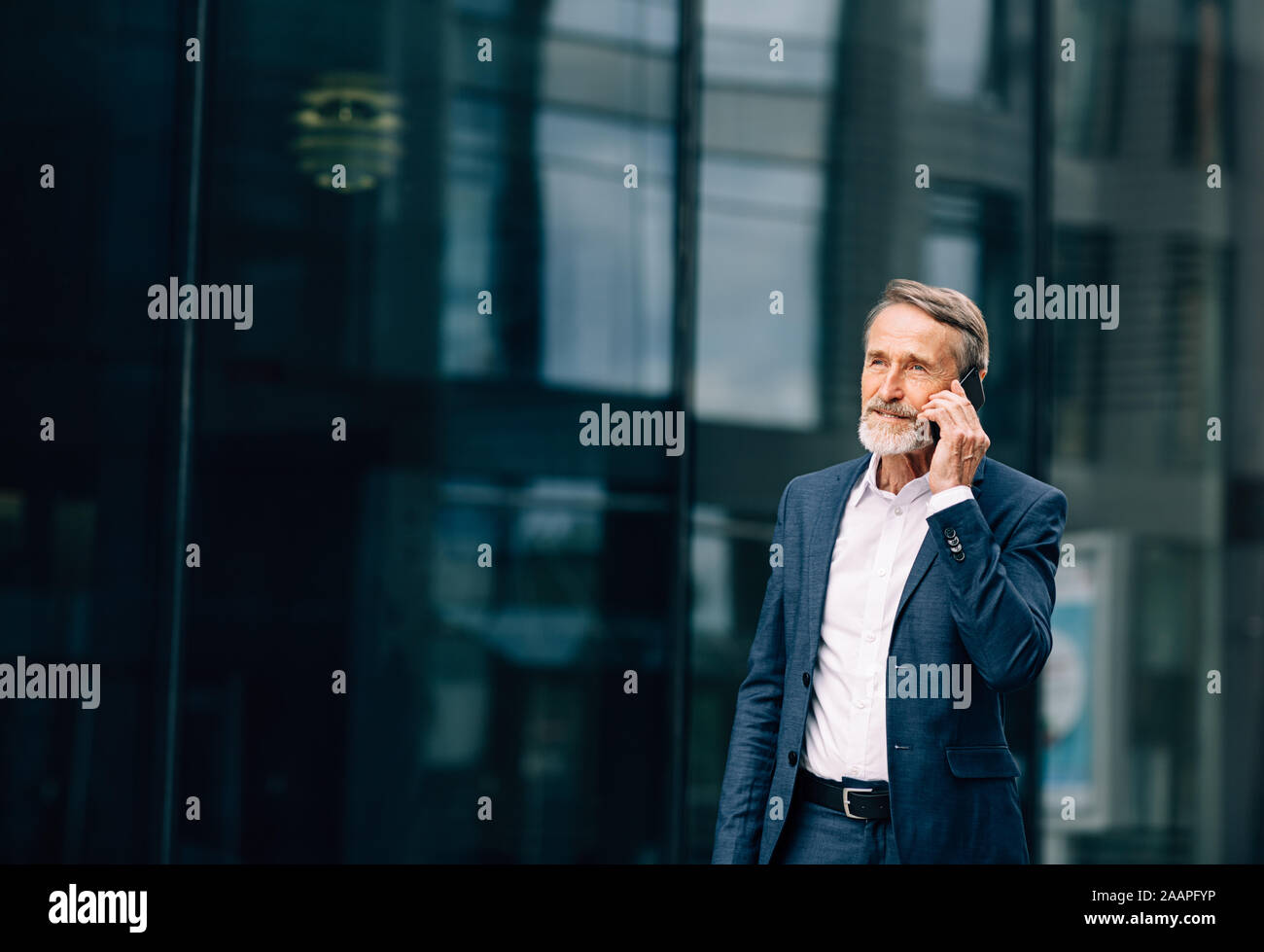 Senior businessman walking at office building et talking on cell phone Banque D'Images