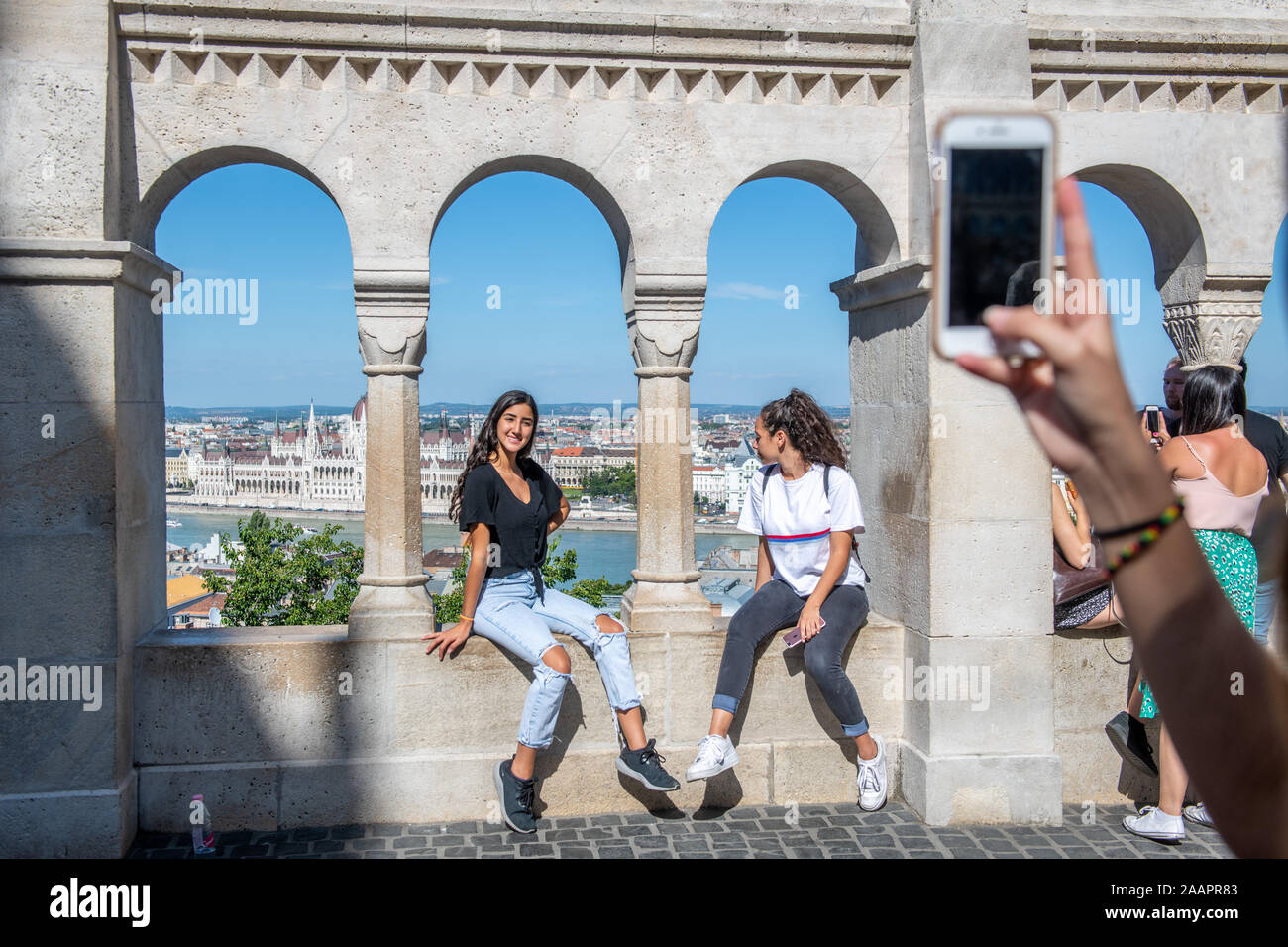 Une paire de femmes s'asseoir sur un balcon à l'Halaszbastya et poser pour une photo avec les toits de Budapest dans l'arrière-plan, Budapest, Hongrie Banque D'Images