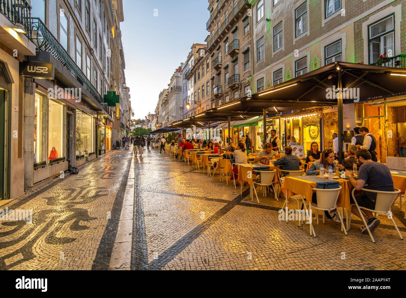 Des gens assis à des tables à l'extérieur des restaurants sur une rue de ville , Lisbonne, Portugal Banque D'Images