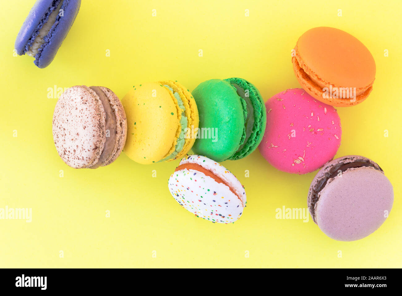 Biscuits macaron français colorés sucré sur fond jaune pastel, vue du dessus Banque D'Images