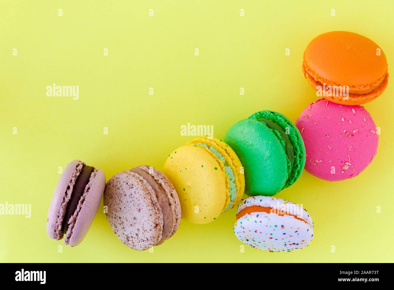 Biscuits macaron français colorés sucré sur fond jaune pastel, vue du dessus Banque D'Images