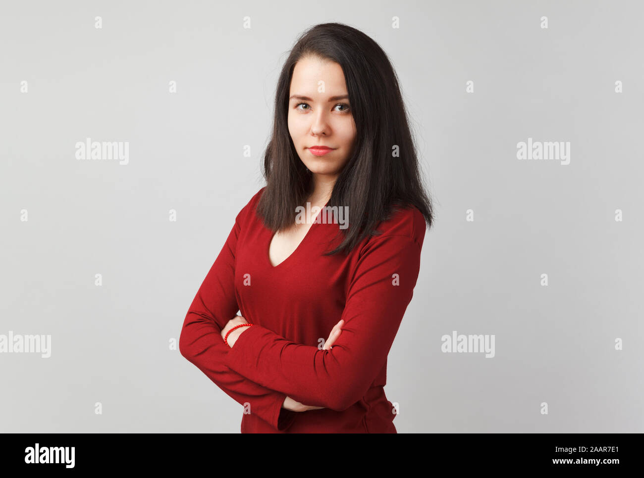 Jolie jeune fille européenne avec les bras croisés en coton rouge shaker stitch deep v-neck sweater isolés sur fond gris. Banque D'Images