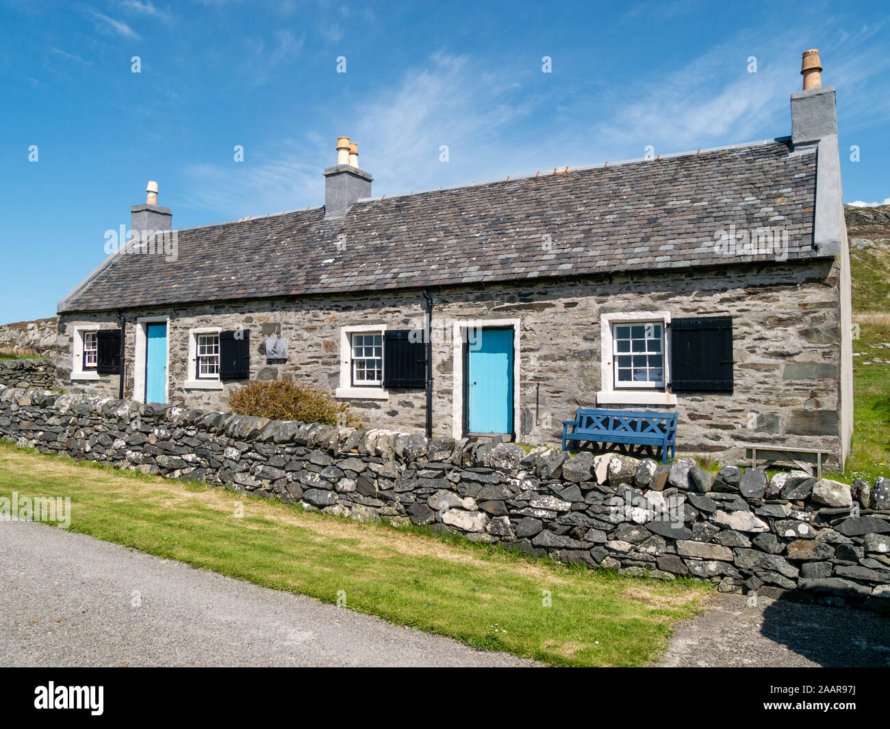 Rangée de cottages en pierre ancienne smart avec des volets aux fenêtres et portes bleues utilisées par la RSPB sur l'île de l'Oronsay, Colonsay, Ecosse, Royaume-Uni Banque D'Images