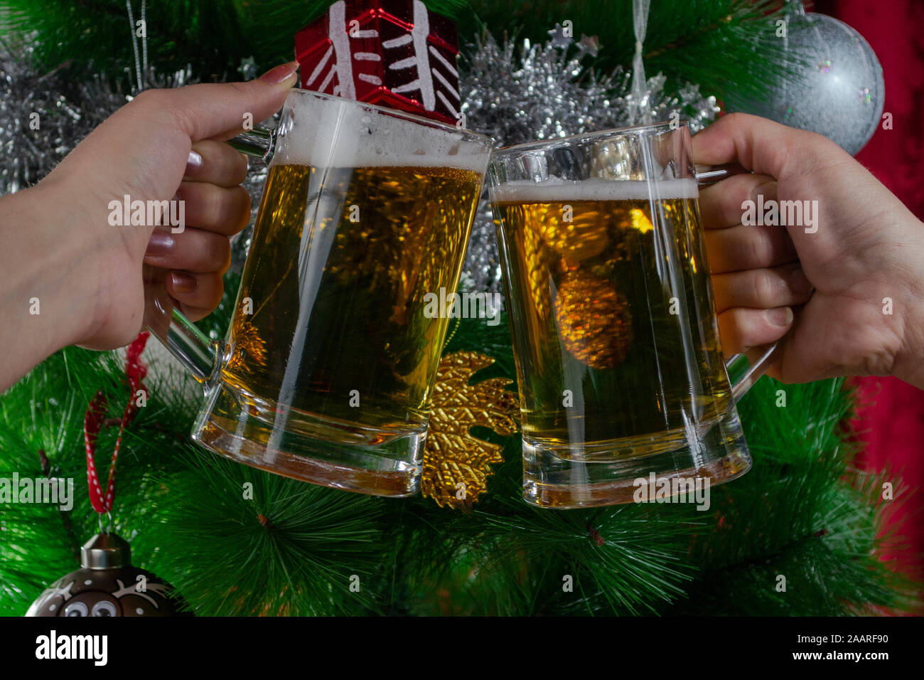 Bonne Année. Deux personnes en train de griller deux pintes de bière légère devant l'arbre de Noël, photo-illustration Banque D'Images