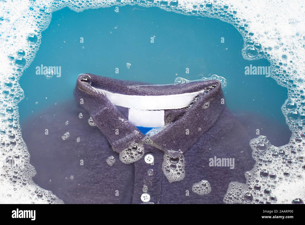 Polo shirt faire tremper dans de l'eau détergent en poudre la dissolution, lave-linge doux. Concept de blanchisserie Banque D'Images
