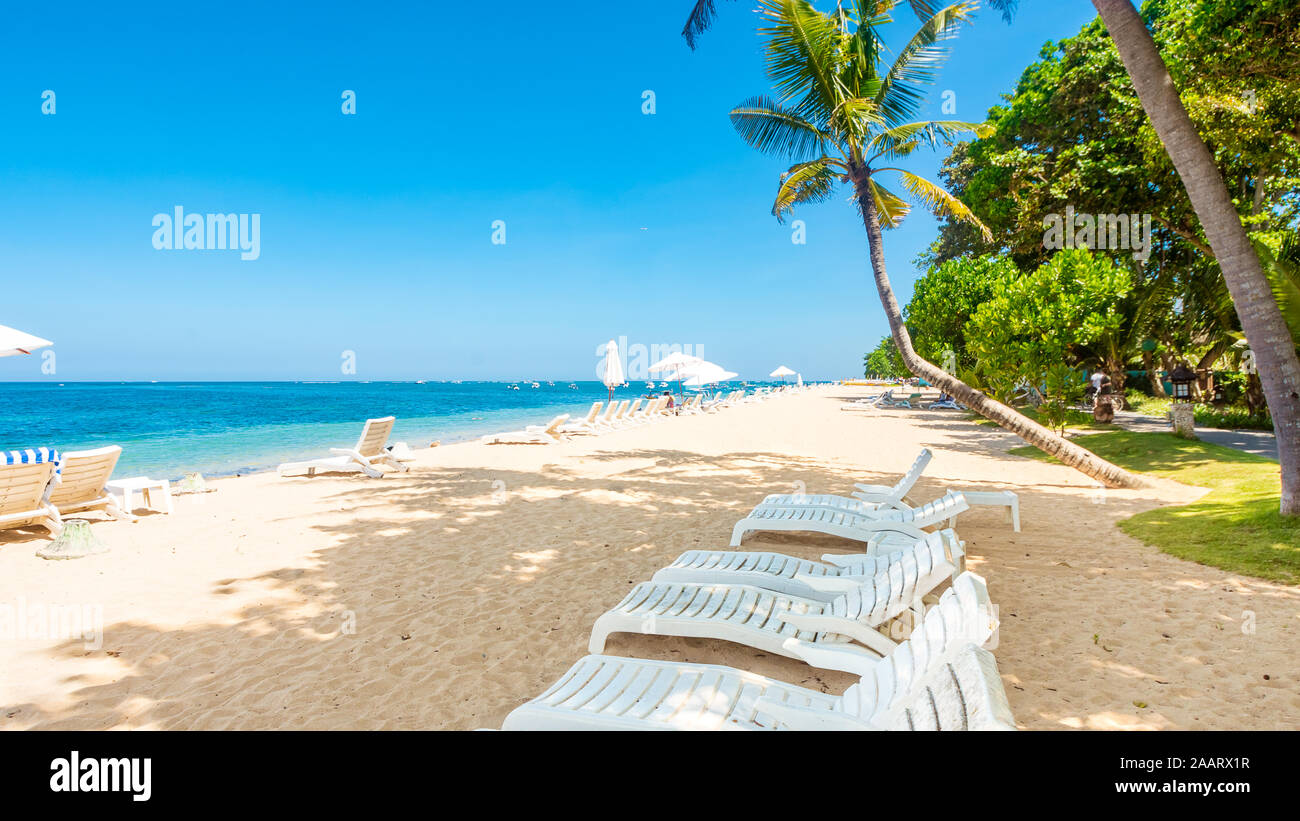 Chaises longues sur une belle plage tropicale sur une journée ensoleillée - vacances tropicales concept image avec copie espace pour le texte Banque D'Images