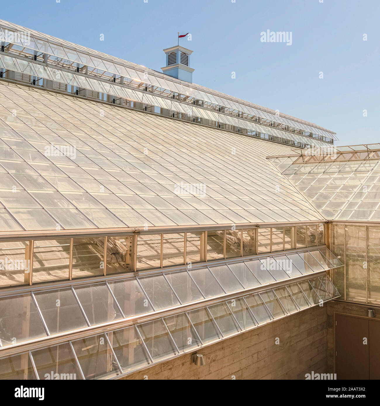 De l'extérieur d'un cadre carré de panneaux de verre à effet de serre sur le toit et sur le mur de brique Banque D'Images