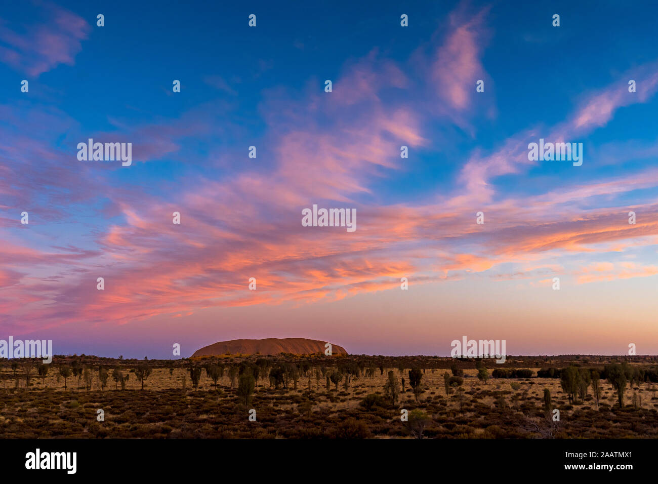 Uluru, aussi connu sous le nom de Ayers Rock, au coucher du soleil avec d'intéressantes formations nuageuses au-dessus. Territoire du Nord, Australie. Banque D'Images