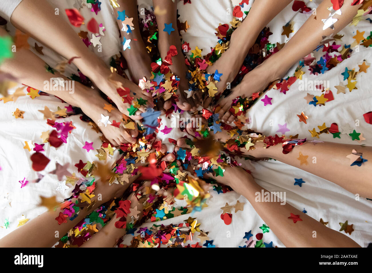 Les jambes des femmes diverses sur le lit recouvert de confettis colorés, gros plan Banque D'Images