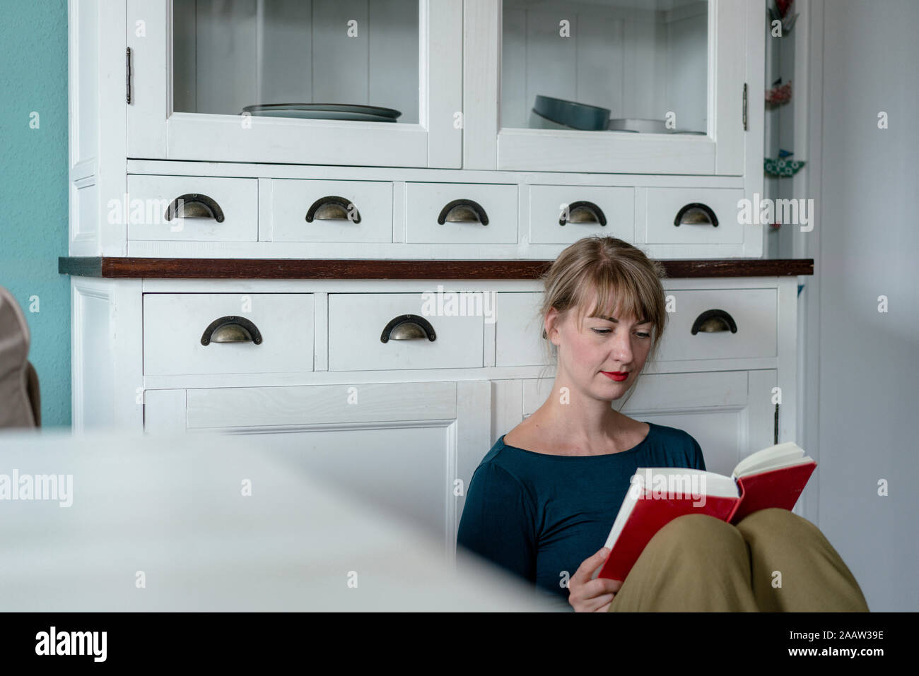 Portrait de femme assise dans la cuisine la lecture d'un roman Banque D'Images