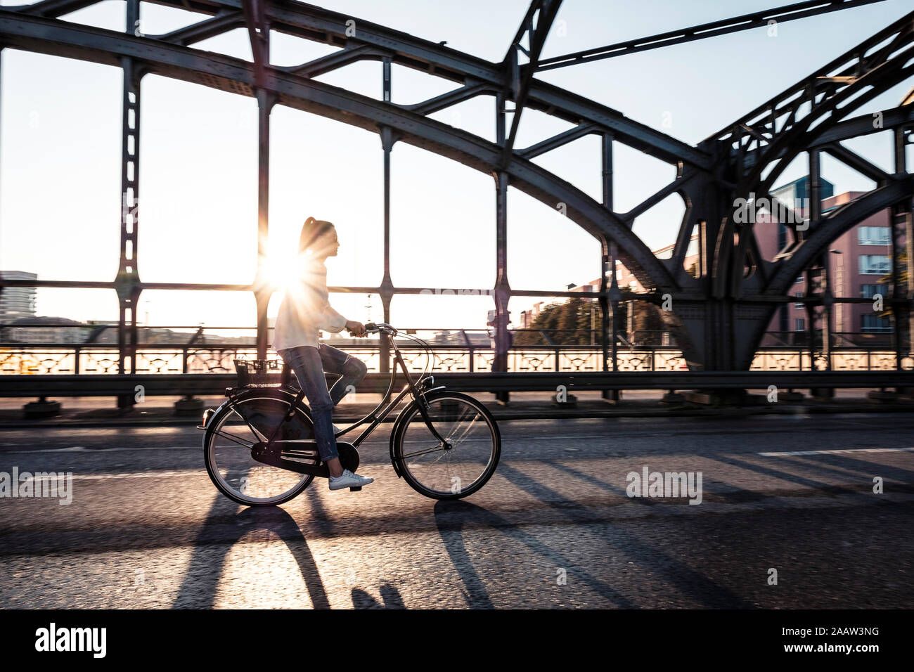 Les jeunes cyclistes sur un pont au coucher du soleil Banque D'Images
