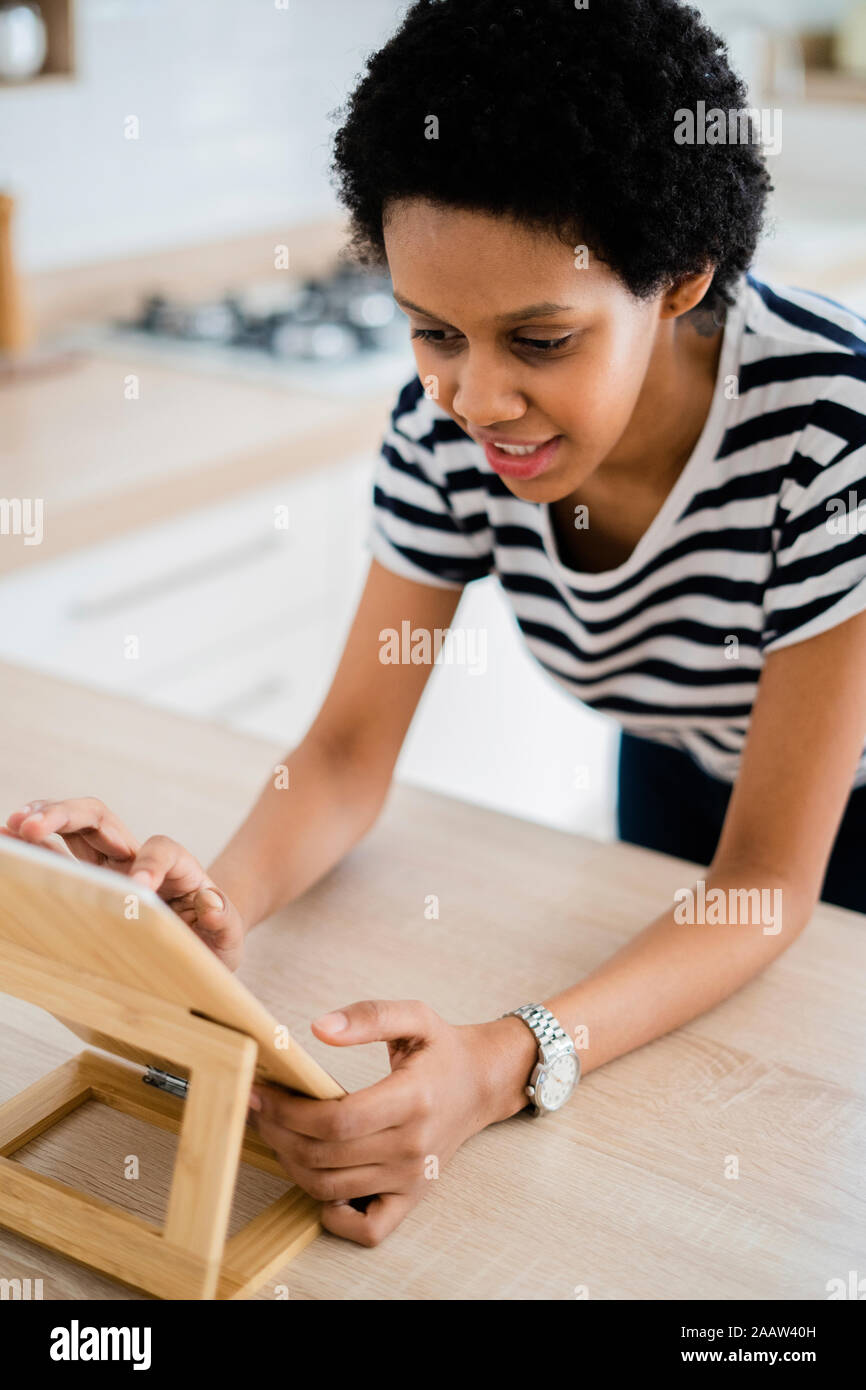 Young woman using tablet dans la cuisine à la maison Banque D'Images