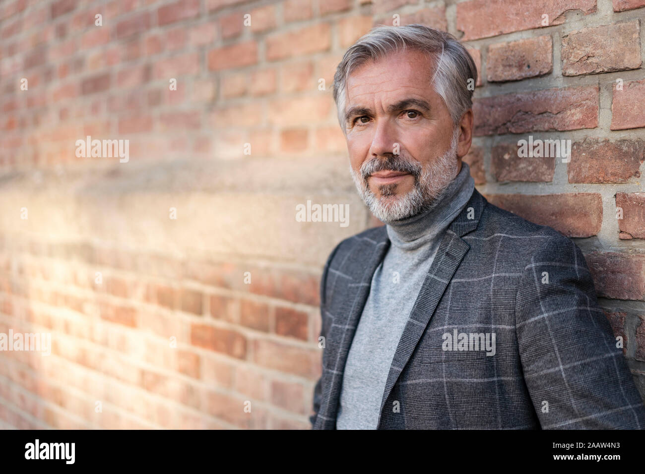 Portrait of mature businessman à la mode à un mur de briques Banque D'Images