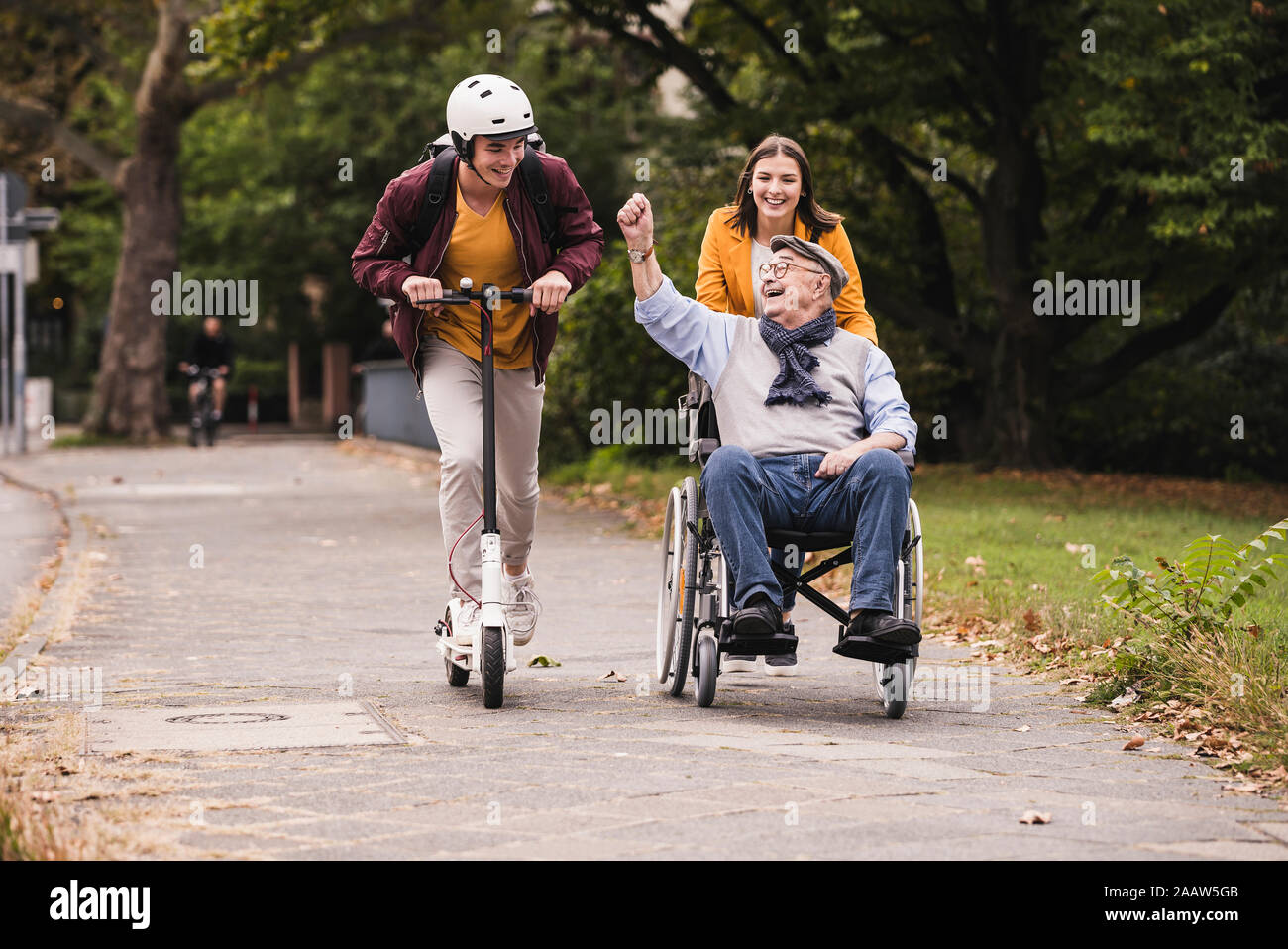 Senior man in wheelchair having fun avec ses petits-enfants adultes à l'extérieur Banque D'Images