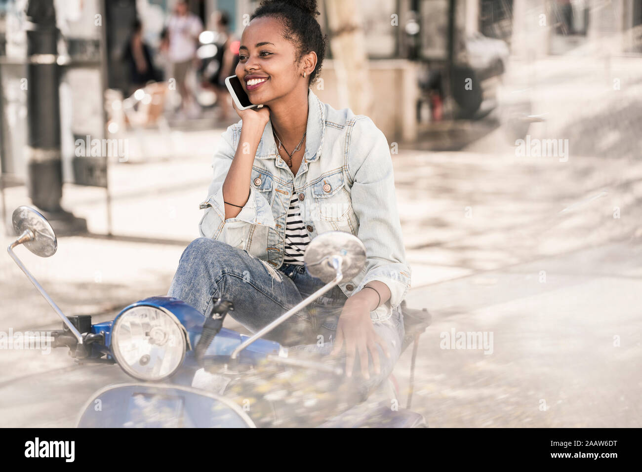 Happy young woman with motor scooter sur le téléphone dans la ville, Lisbonne, Portugal Banque D'Images