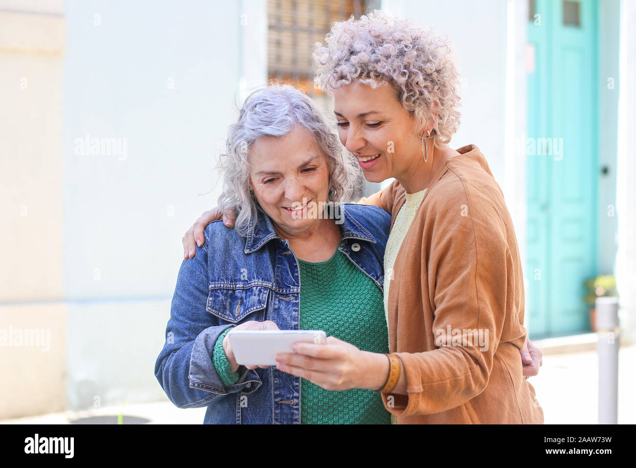 Maman avec ses supérieurs à l'aide de sa fille adulte smartphone outdoors Banque D'Images