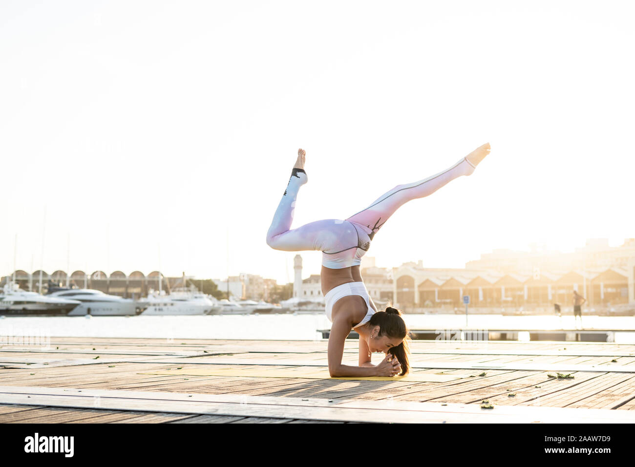 Asian woman practicing yoga on a pier à l'Harbour Banque D'Images