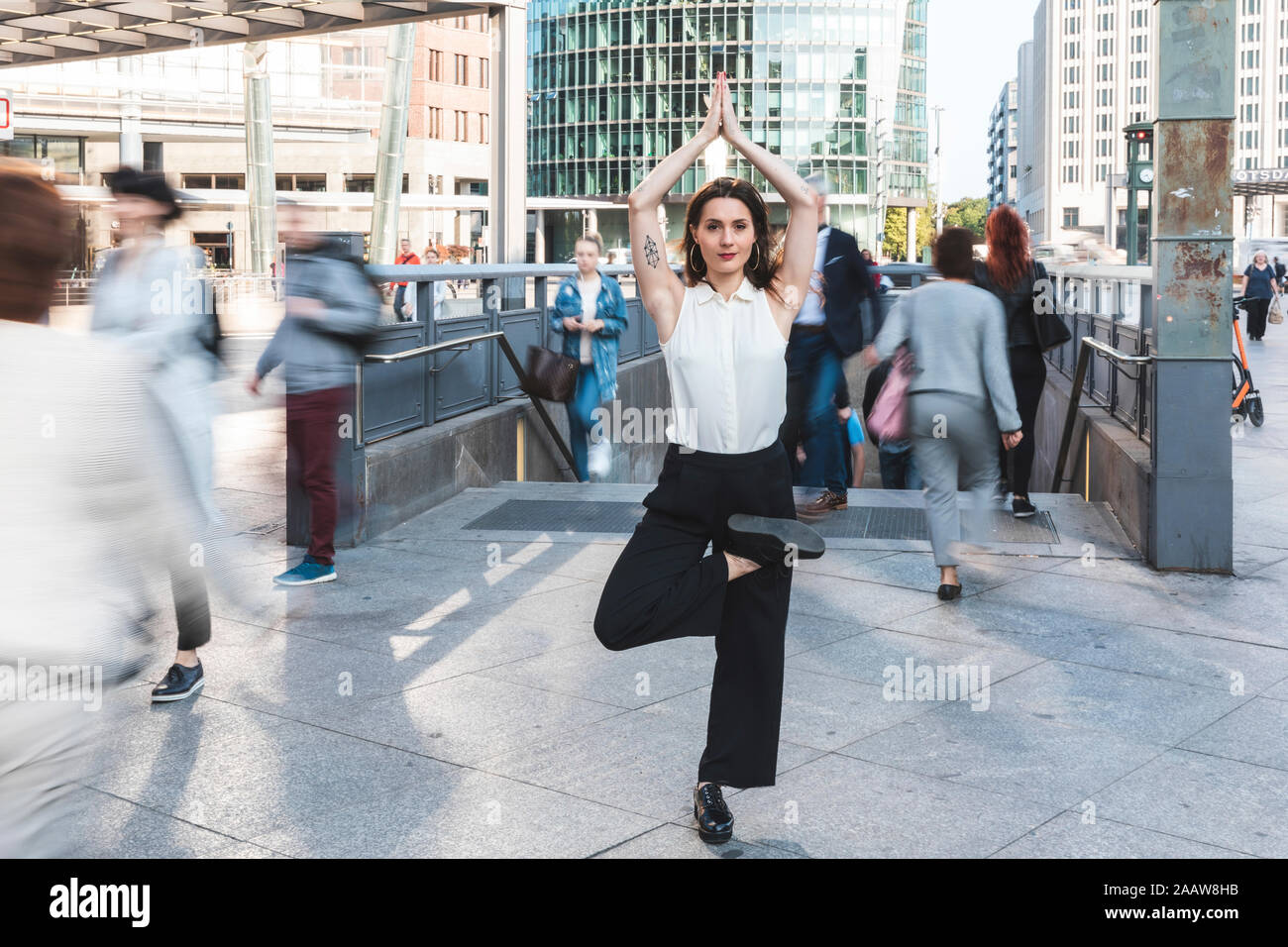 Young businesswoman pratiquant le yoga dans la ville à l'heure de pointe, Berlin, Allemagne Banque D'Images