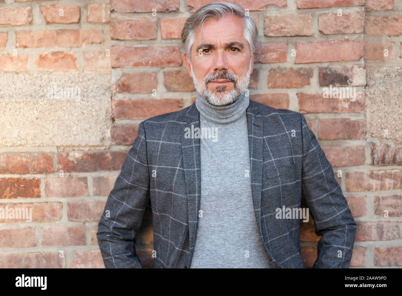 Portrait of mature businessman à la mode à un mur de briques Banque D'Images
