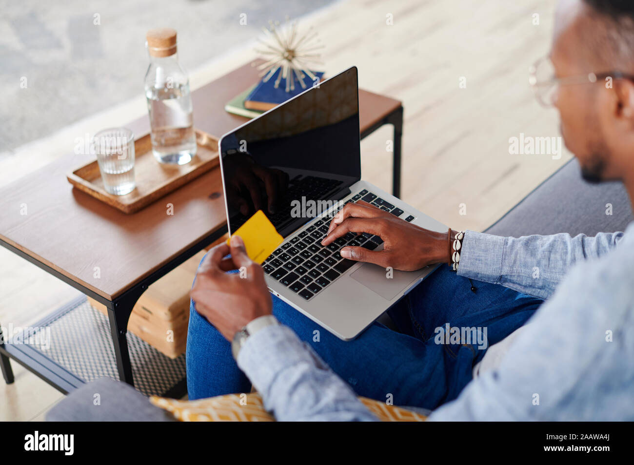 Jeune homme à l'aide d'ordinateur portable à la salle de séjour Banque D'Images