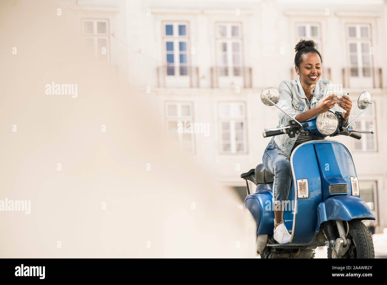 Souriante jeune femme avec scooter et du téléphone mobile dans la ville, Lisbonne, Portugal Banque D'Images