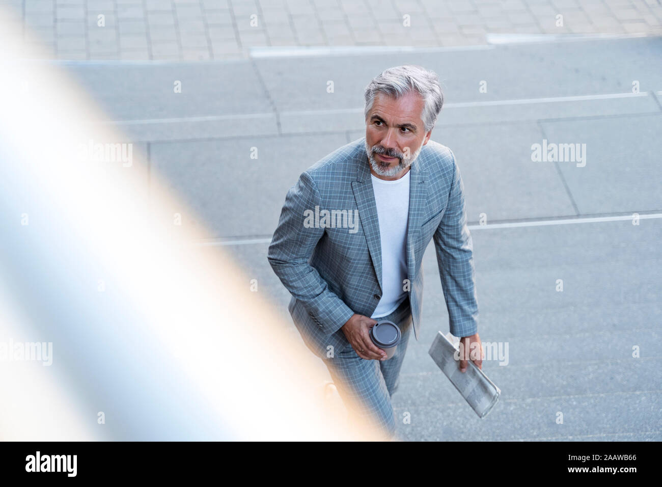 Vue du dessus de l'homme d'âge mûr avec du papier journal et café à emporter Banque D'Images