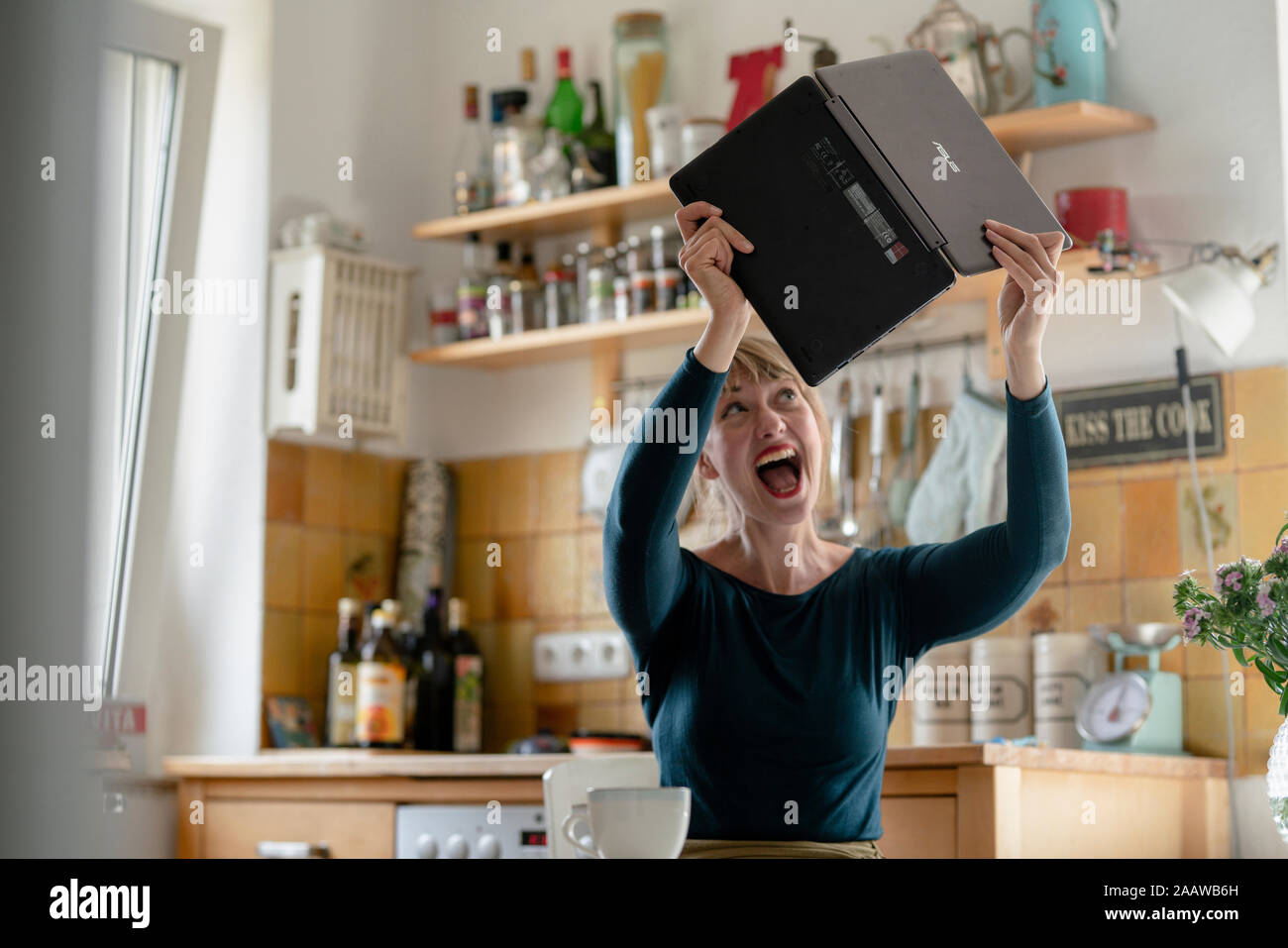 Portrait de screaming woman with laptop dans la cuisine Banque D'Images