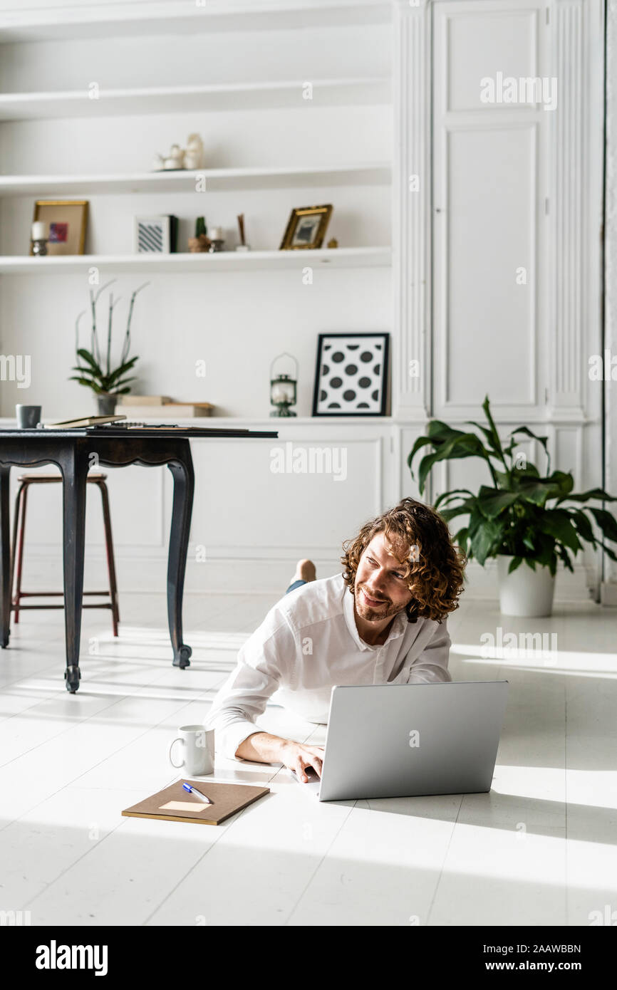 Homme étendu sur le sol à l'aide d'ordinateur portable Banque D'Images