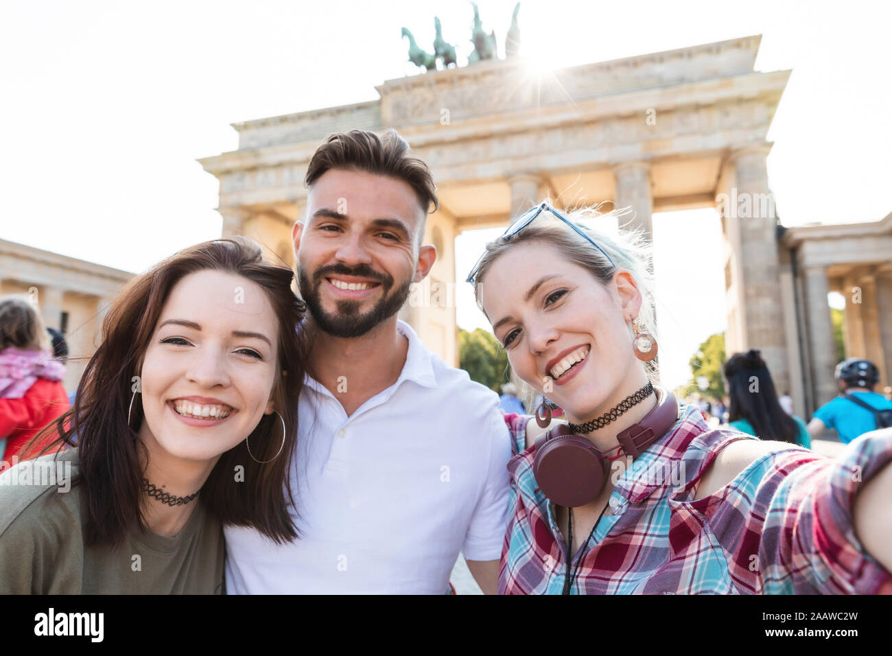 Portrait de trois amis heureux en tenant un téléphone cellulaire avec selfies en face de la porte de Brandebourg, Berlin, Allemagne Banque D'Images