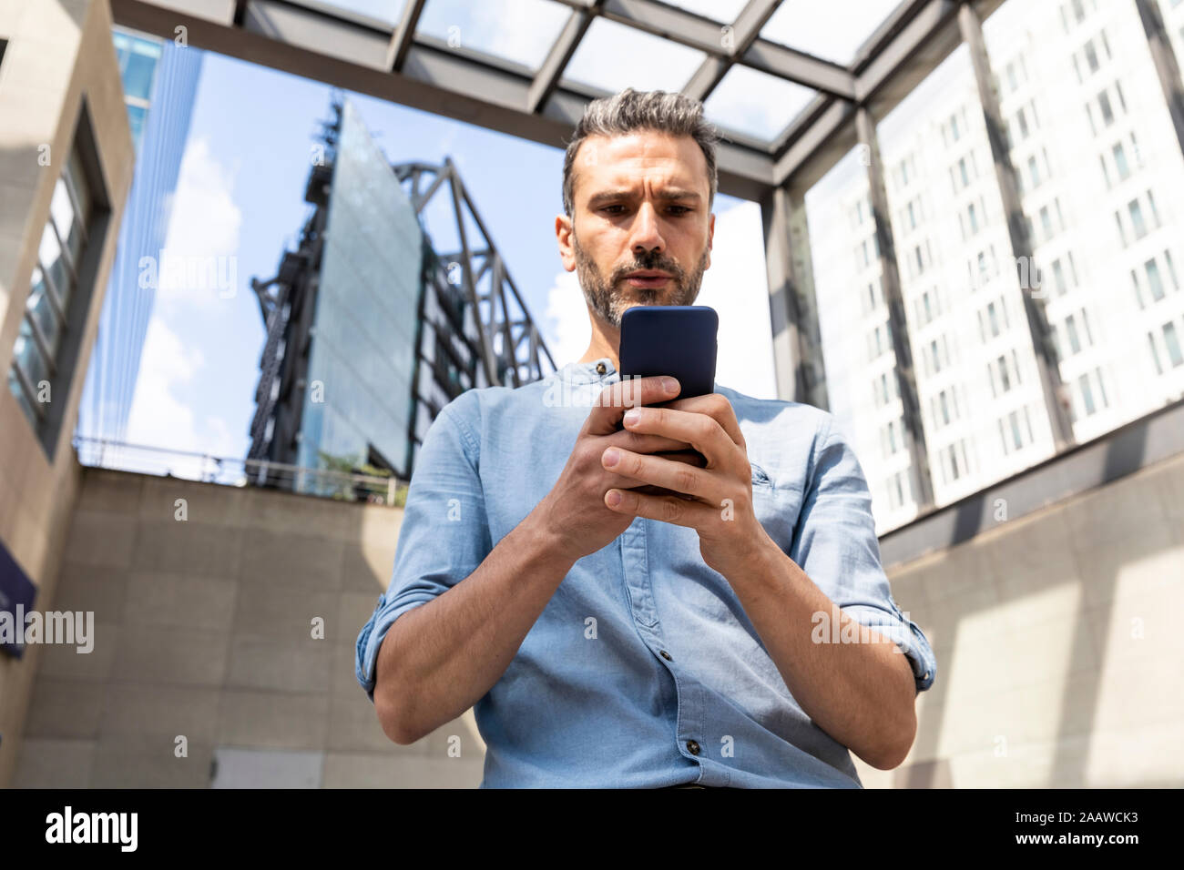 Serious businessman looking at le smartphone dans la ville, Berlin, Allemagne Banque D'Images