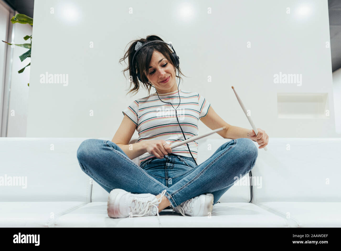 Smiling woman écouter de la musique et jouer avec baguettes de tambour Banque D'Images