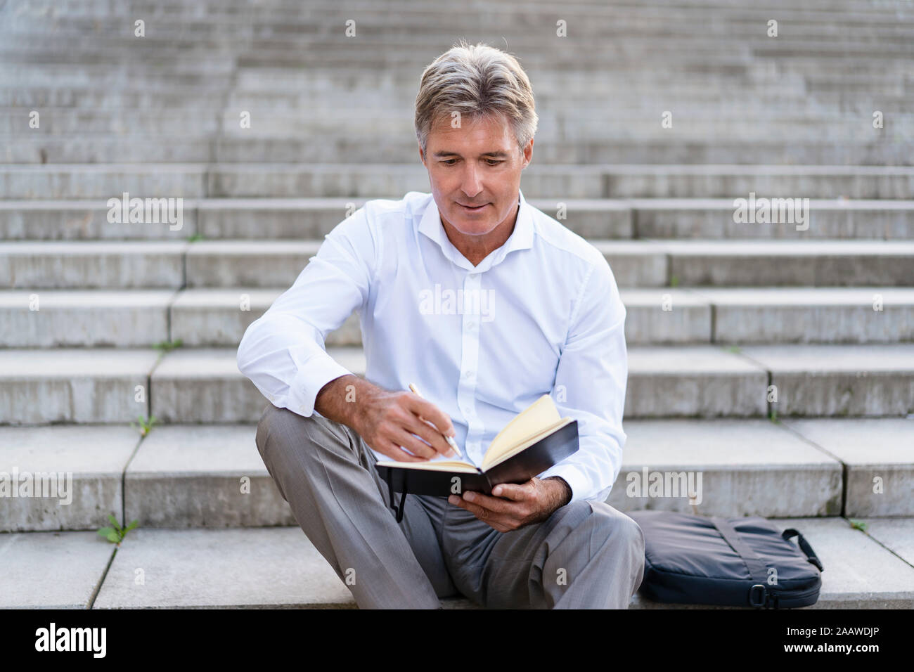 Mature businessman sitting on stairs à ordinateur portable à Banque D'Images