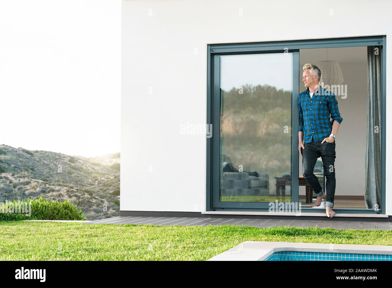 Homme debout devant sa maison moderne avec piscine à la recherche sur les paysages Banque D'Images Homme debout devant sa maison moderne avec piscine à la recherche sur les paysages Banque D'Images