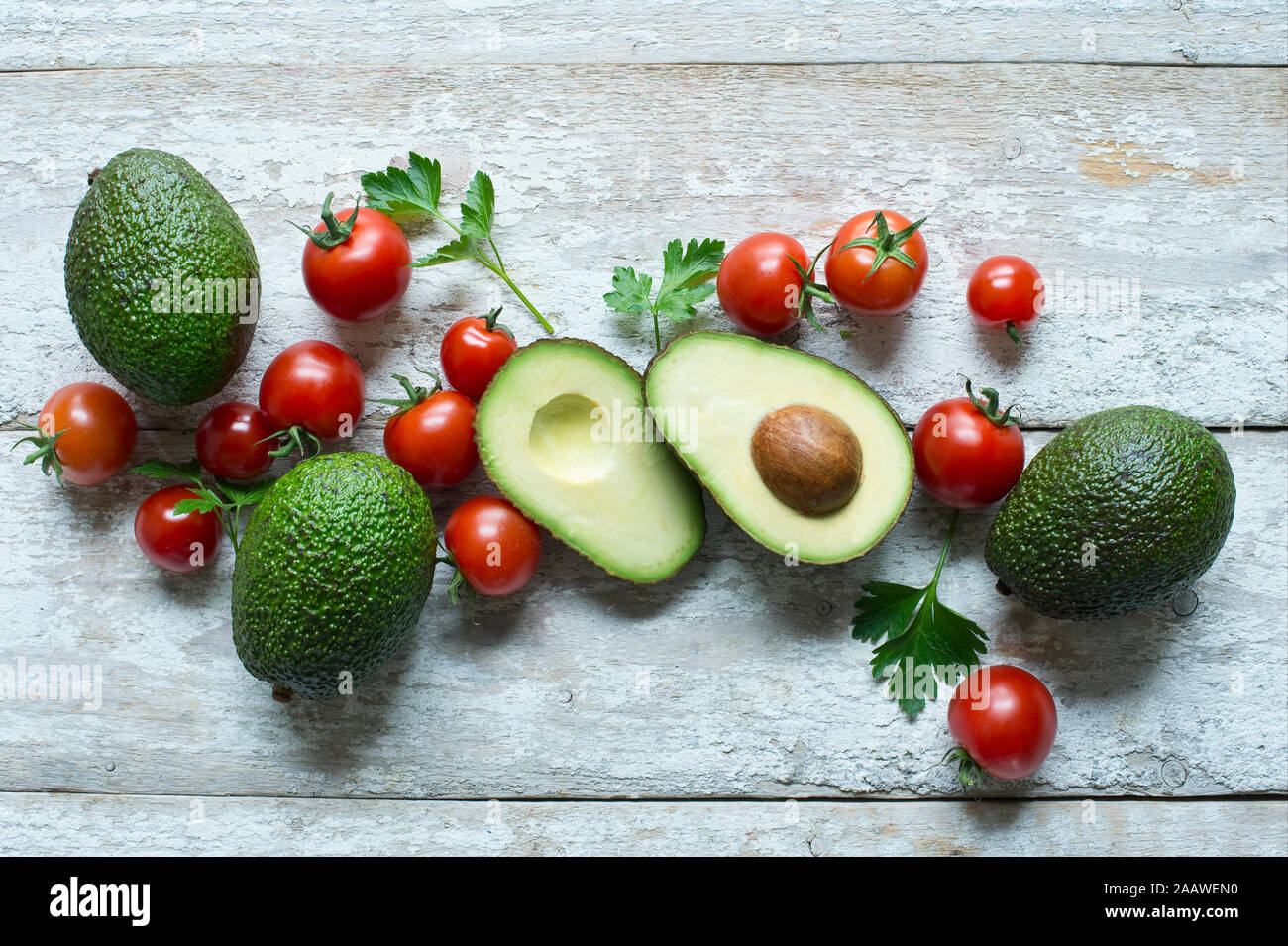 Tourné directement au-dessus d'avocats avec tomates et le persil sur table en bois Banque D'Images