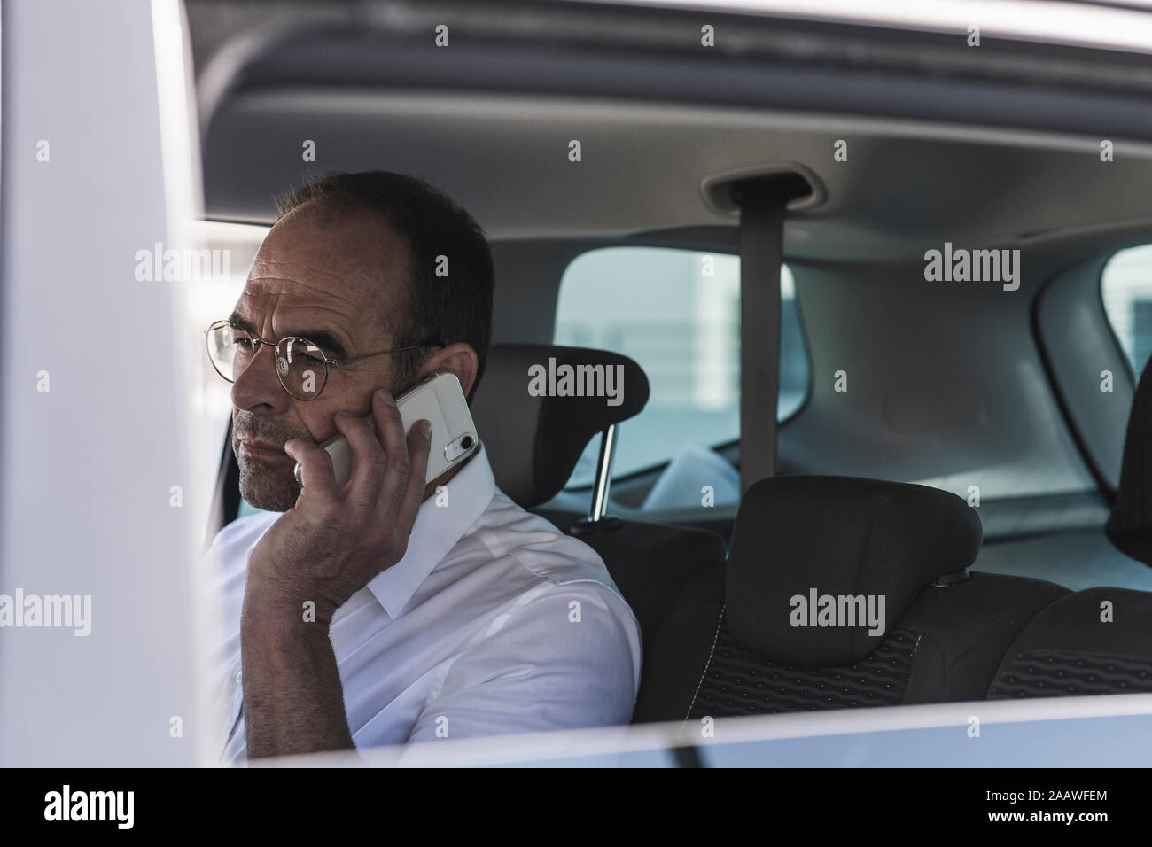 Portrait of mature businessman on the phone in car Banque D'Images