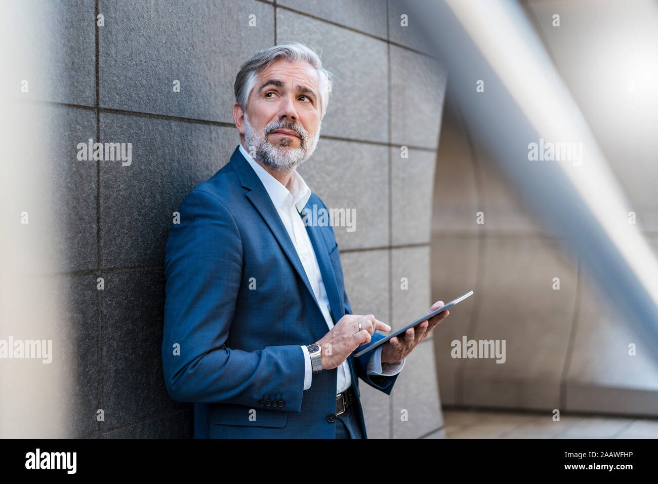 Businessman standing à un mur à l'aide de tablet Banque D'Images